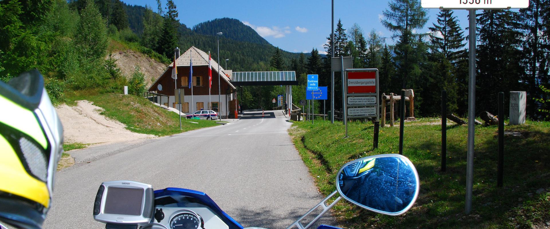 Motorradfahrer auf der Passhöhe des Paulitschsattel, mit Blick auf das Passschild