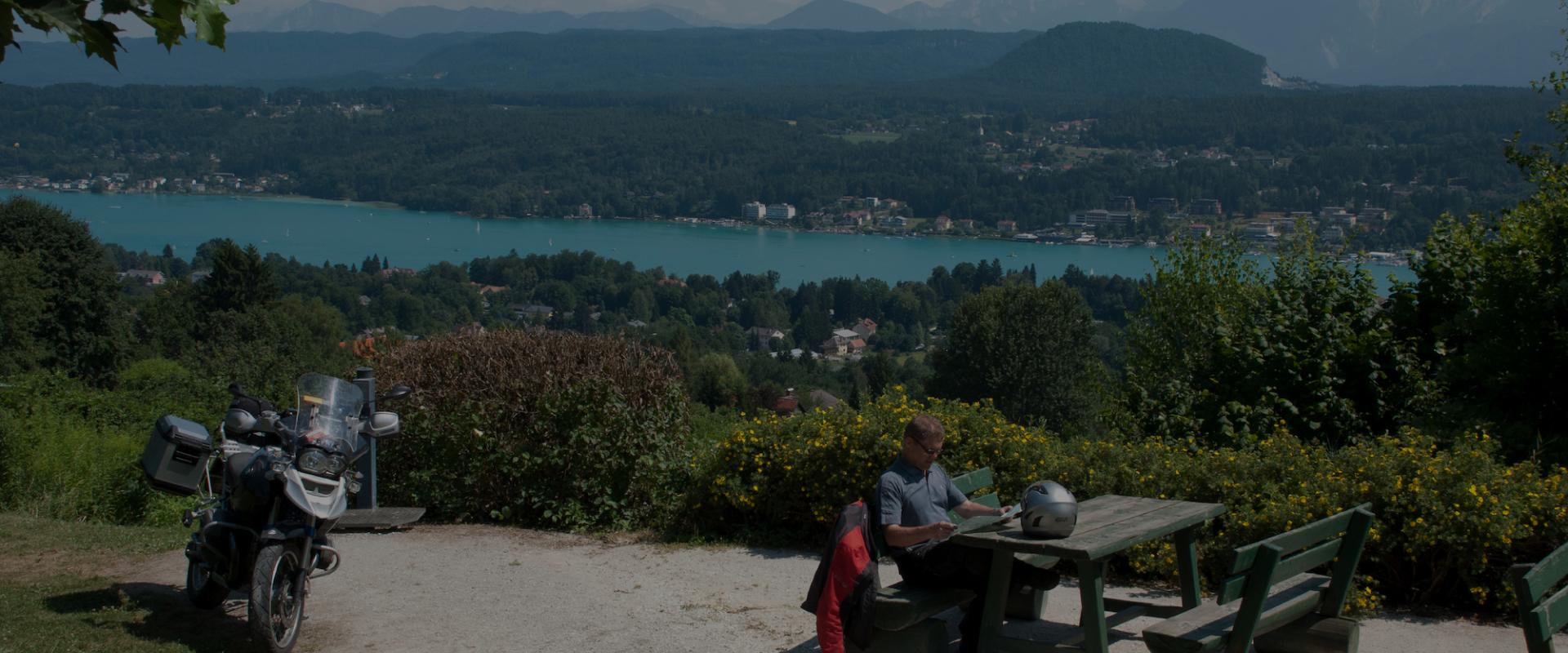 Motorradfahrer macht Pause oberhalb eines Sees auf Motorradtour in Kärnten
