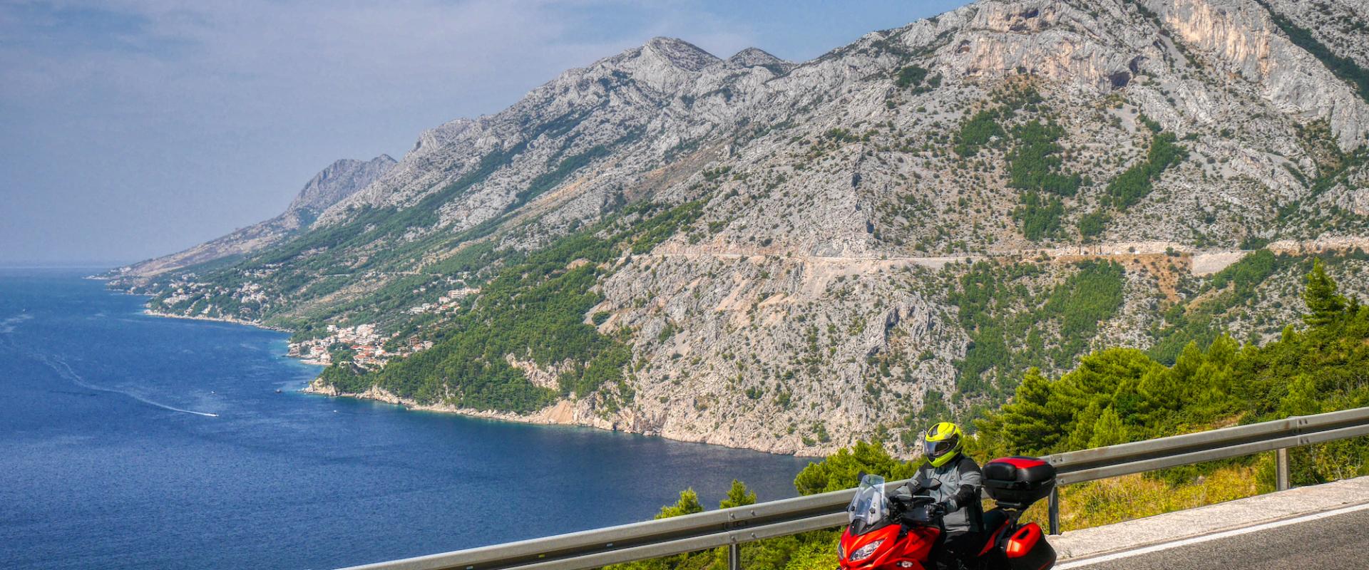 Ein rotes Motorrad fährt auf der Jadranska Magistrala an der  Makarsa Riviera entlang