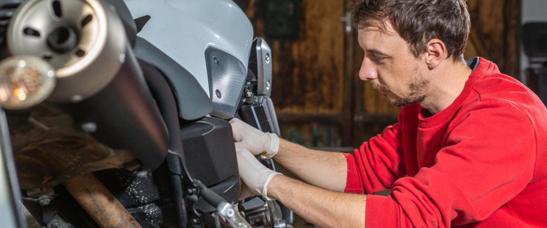 Mann mit rotem Pullover schraubt an einem Motorrad