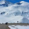 Motorradfahrer in einer Kehre der Grossglockner Hochalpenstraße, mit Blick auf schneebedeckte Berge