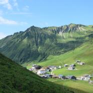 Ausblick des Faschinajochs, auf Dorf, Wiesen und Berge 