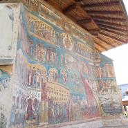Bunte Fresken zeigen biblische Szenen und Heilige an der Außenwand in einem rumänischen orthodoxen Kloster, geschützt unter einem Vordach