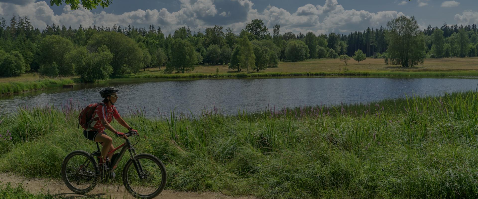 Ebikerin fährt an einem See in Mecklenburg-Vorpommern entlang