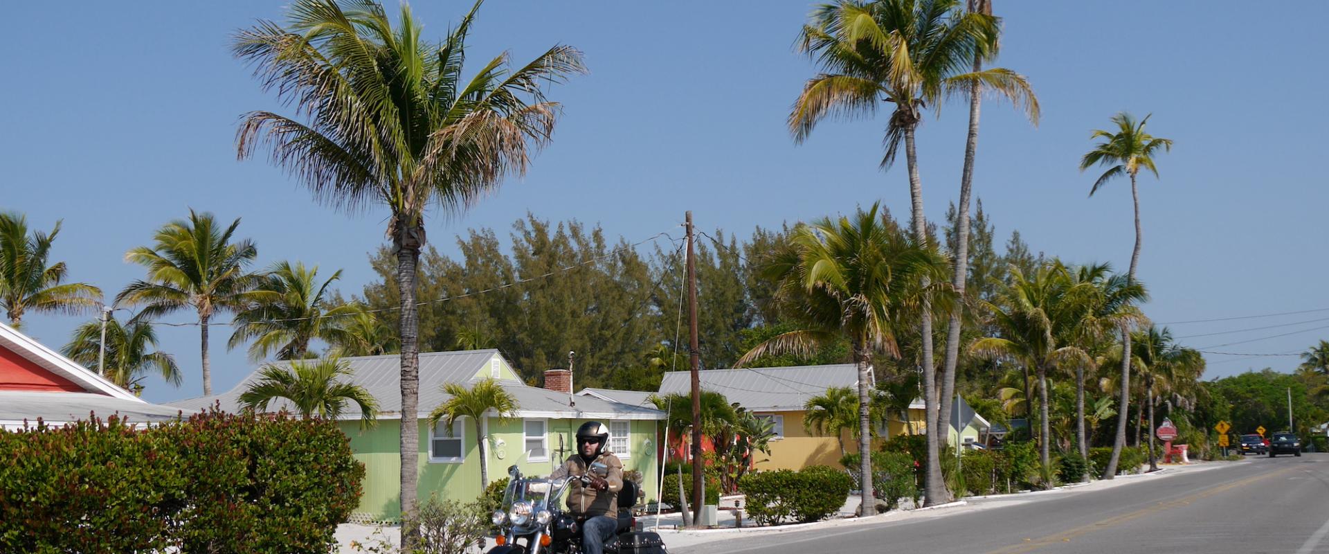 Motorradfahrer mit seiner Harley auf Sanibel Island mit Palmen und bunten Häusern