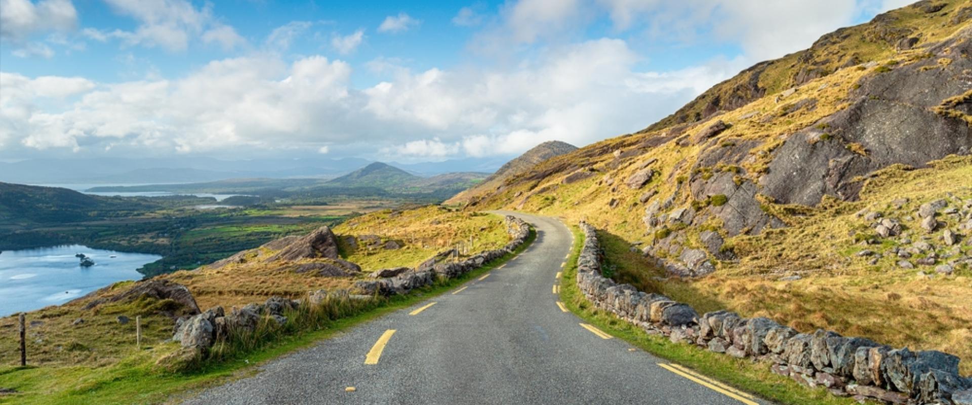 Schmale einspurige Straße führt durch eine hügelige Landschaft Irlands