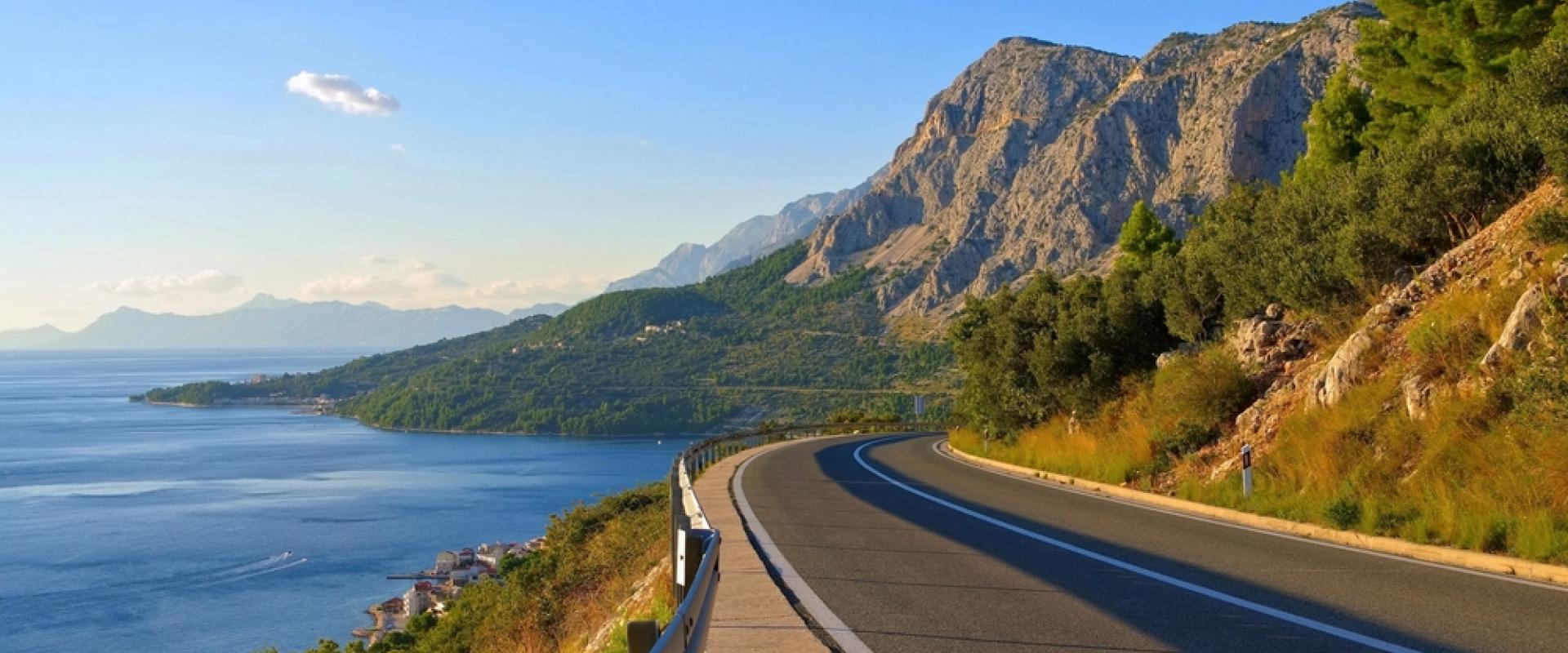 Eine Straße schlängelt sich in Kroatien an der Küste und am Meer entlang. Rechts ist das Meer und links sind Bäume und Berge 