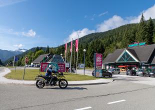 Motorradfahrer auf dem Wurzenpass, mit einem Geschäft im Hintergrund.jpg