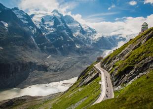 Motorradfahrer unterwegs auf der Großglockner Hochalpenstraße, mit Blick aufs Tal und die umliegenden Berge