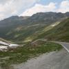 Schmale geteerte Straße durch grüne Landschaft mit Bergen in Österreich 