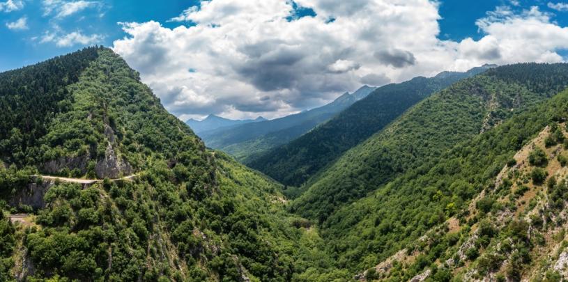 Ein Tal im Agrafa Gebirge, links und grüne rechts Berge mit Bäumen, bewölkter Himmel