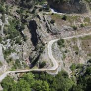 Blick auf eine Schlucht durch die sich eine schmale Straße im Agrafa Gebirge schlängelt, umgeben von Bäumen und Geröll