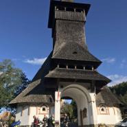 Motorradfahrer vor traditioneller Holzkirche mit strohgedecktem Dach des Barsana Klosters unter blauem Himmel