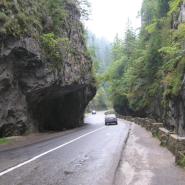 Eine Straße mit 2 Autos schlängelt sich durch den Bicaz Canyon, sie führt durch eine natürliche Felsformation 