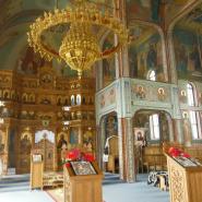 Das Innere einer orthodoxen Kirche eines rumänischen Klosters mit Wandmalerei, Ikonostase und einem großen goldenen Kronleuchter