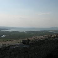 Aussicht von der Enisala Burg, mit Blick auf die weite Landschaft,  Im Vordergrund sind alte Mauerreste sichtbar, dahinter öffnet sich der Blick auf zahlreiche Wasserflächen und Grünflächen