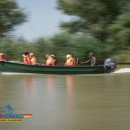 Motorboot mit Personen in orangen Schwimmwesten auf einem Fluss mit  Motonomad Logo versehen